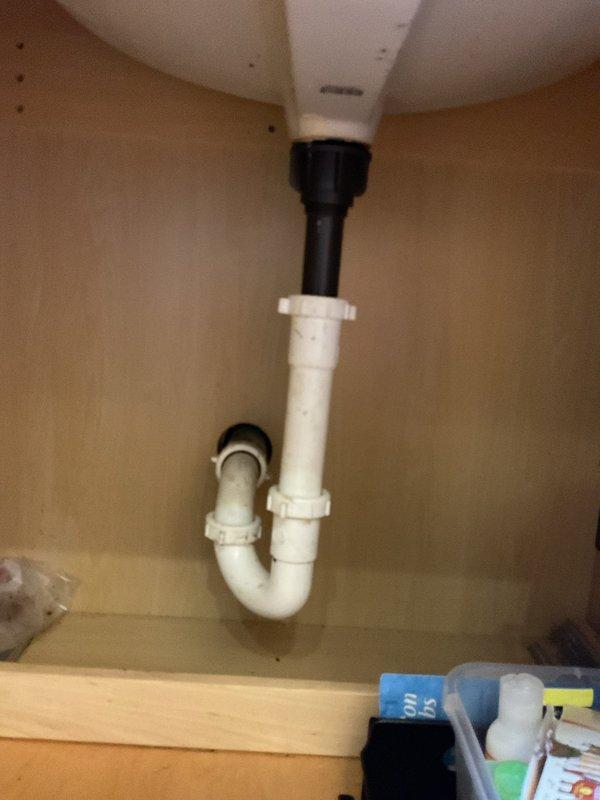 Replaced kitchen sink P-trap assembly with new white PVC piping and slip-joint fittings. Tested drain system for proper flow and verified no leaks at connections. System operating correctly with clear water drainage confirmed.