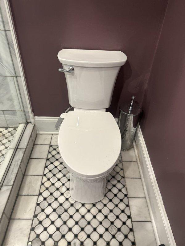 Completed plumbing service call for bathroom fixture assessment and documentation. Inspected toilet installation in residential bathroom with octagonal tile flooring and glass shower enclosure. Verified proper operation of two-piece white porcelain toilet fixture, confirmed secure mounting to floor, and checked for any signs of leaks or water damage around base and supply connections. All fixtures found to be in good working condition with no immediate repairs required at time of visit.