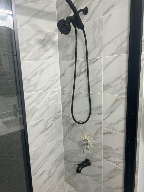 Completed post-inspection plumbing assessment for condominium unit, evaluating multiple minor plumbing concerns identified during home inspection. Inspected modern shower installation featuring dual showerhead system with matte black fixtures, single-handle valve control, and tub spout mounted on marble-effect tile surround with black-framed glass enclosure. Assessed shower drain assembly and provided estimate for replacement of drain cover components. Examined under-sink plumbing assembly including disposal unit connection, P-trap configuration, and associated drainage connections to ensure proper function and code compliance.