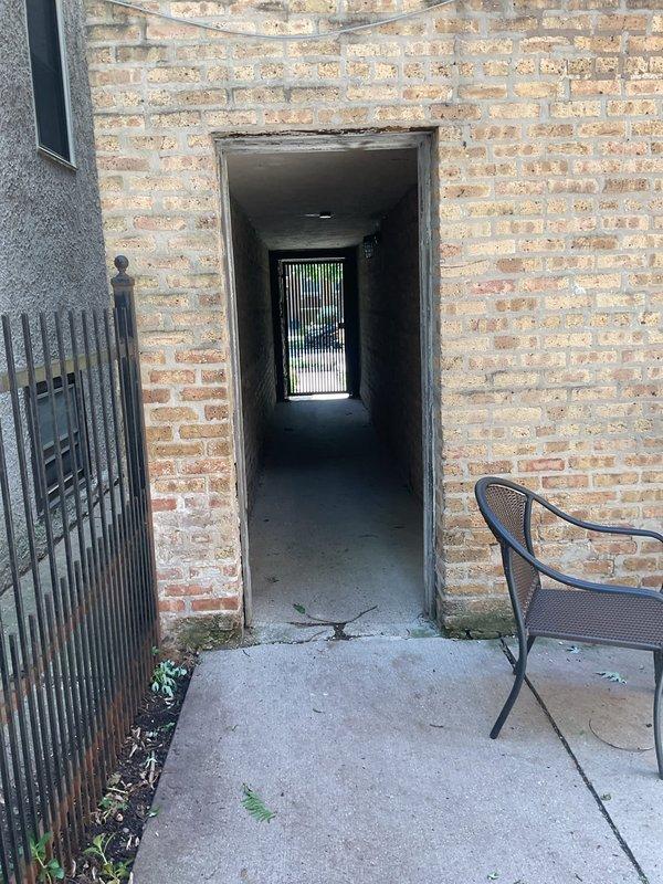 Responded to a slow-draining communal area drain that leads to a catch basin in the back exterior stairwell and patio area of a commercial building. Conducted inspection of the affected ground drain, catch basin, and additional ground drains in the area to assess blockage severity and determine clearing requirements. Documented site conditions with photographs showing the stairwell entrance with floor drain and the brick passageway patio area for estimate preparation purposes.