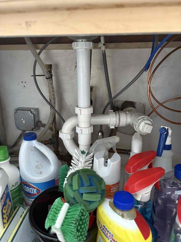 Conducted quality assurance inspection of recently completed water repipe installation, water filtration system, and ice maker line connections. Documented plumbing system featuring new copper piping with foam insulation, backflow prevention valve assembly with bypass capability, and proper hot/cold water line identification in basement crawl space area. Verified under-sink P-trap configuration and supply line connections are functioning correctly per installation specifications.