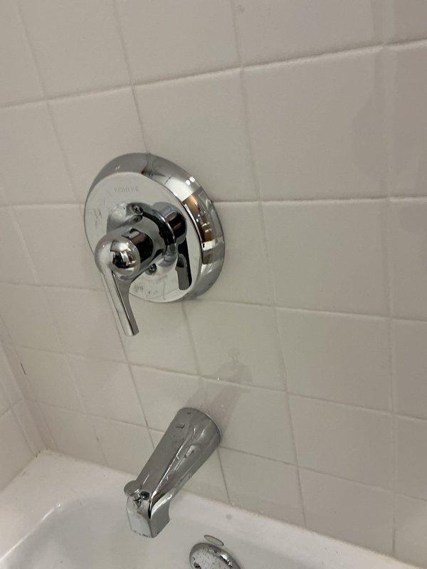Responded to service call for malfunctioning Kohler single-handle shower valve with improper hot/cold water mixing and reduced hot water flow. Diagnosed cartridge failure causing temperature control issues and restricted flow on hot side. Removed chrome lever handle and circular escutcheon plate from white subway tile wall. Extracted and replaced defective valve cartridge with manufacturer-specified replacement part. Tested temperature mixing across full range of handle positions and verified proper hot water flow and pressure. Reassembled trim components and confirmed leak-free operation.