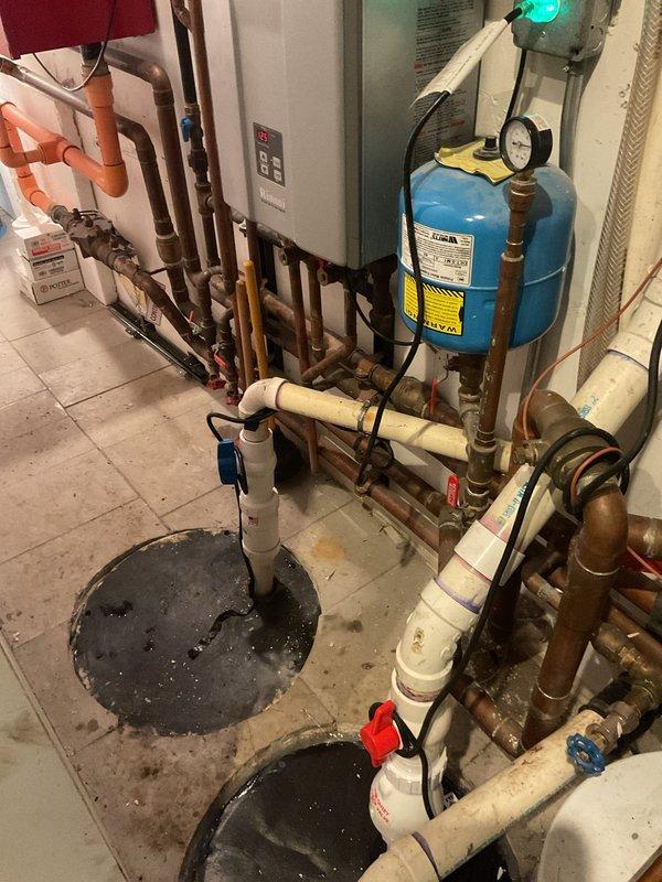 Responded to service call for overflowing toilet in 25-year-old residential property. Upon arrival, conducted comprehensive plumbing system inspection including toilet fixture, water supply lines, and drainage connections. Diagnosed and resolved overflow issue by addressing wax ring failure and flange deterioration common in fixtures of this age. Removed and reset toilet with new wax seal and flange hardware to restore proper sealing and prevent future leaks.

During service visit, performed courtesy inspection of home's plumbing infrastructure at customer's request for additional work assessment. Documented existing mechanical room configuration including tankless water heater installation, expansion tank system, water filtration equipment, and associated copper supply piping. All heating and water treatment components appeared to be functioning within normal parameters. Noted dual sump pump basin configuration with PVC drainage system in basement utility area.

Inspected kitchen plum