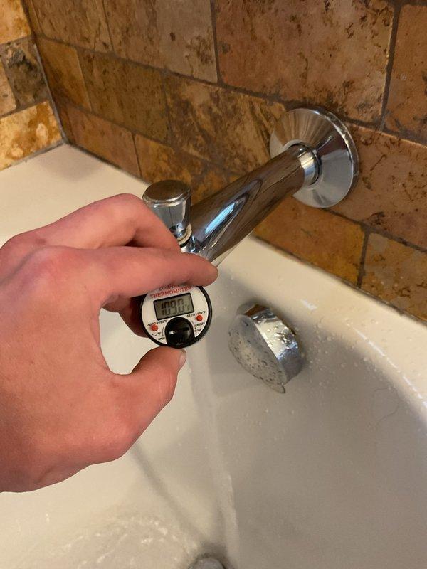 Responded to service call for two plumbing issues: basement toilet flushing failure and second-floor shower temperature problem. Inspected basement ejector pump system and verified operational status of pump components and discharge piping. Tested second-floor shower mixing valve and measured water temperature at tub spout, recording 102.8°F output. Evaluated shower cartridge function and identified temperature regulation issue preventing adequate hot water delivery. Assessed condition of plumbing infrastructure including PVC discharge lines and mechanical components in utility area.