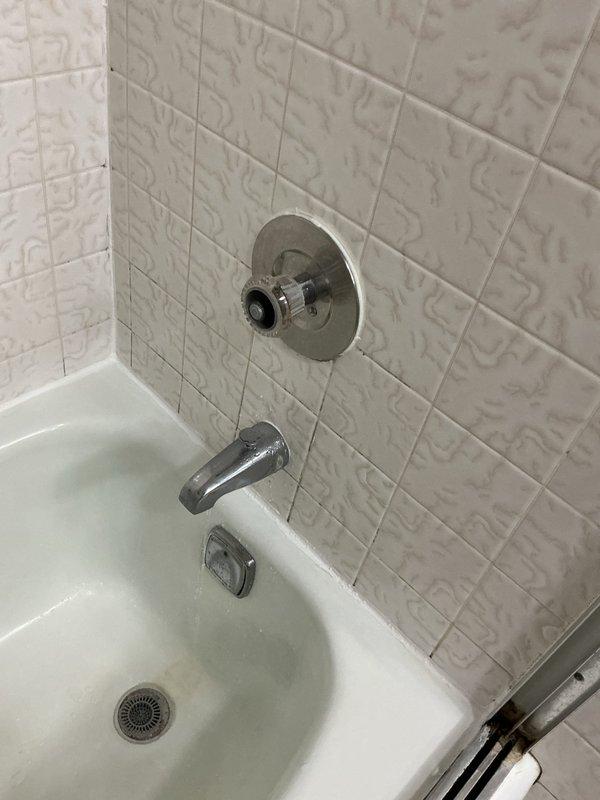 Responded to building shutdown for emergency plumbing repair. Inspected and serviced bathtub shower valve assembly with visible cartridge failure, addressing control mechanism issues affecting water flow and temperature regulation. Accessed basement plumbing infrastructure to diagnose and repair supply line connections associated with bathroom fixtures, working around existing copper piping, shut-off valves, and mechanical systems in crawl space area.