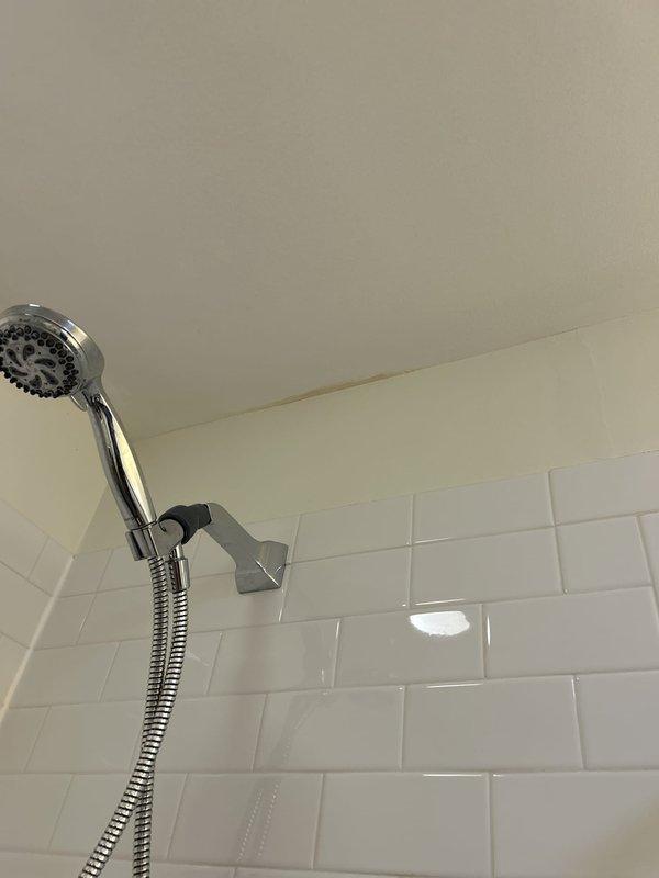 Responded to service call for leaking tub drain in bathroom with skylight and modern tile finishes. Inspected bathroom plumbing system, focusing on bathtub drain assembly and surrounding fixtures including handheld showerhead installation and wall-mounted components. Documented existing conditions showing white subway tile walls, chrome fixtures, and ceiling-mounted ventilation and lighting systems to assess potential leak sources and water damage patterns.