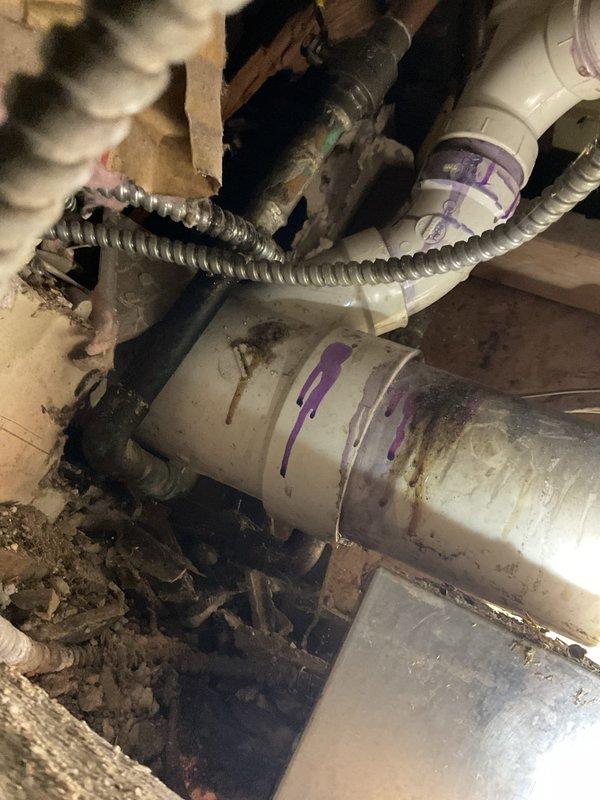 Completed plumbing repair service in residential property involving inspection and documentation of crawlspace plumbing infrastructure and bathroom fixtures. Assessed PVC drainage system beneath structure, examining multiple pipe connections, fittings, and joints for proper function. Documented condition of existing plumbing assembly including flexible conduit installation and various diameter pipe connections in crawlspace area. Verified bathroom fixtures including toilet installation and proper operation in corner-mounted configuration.