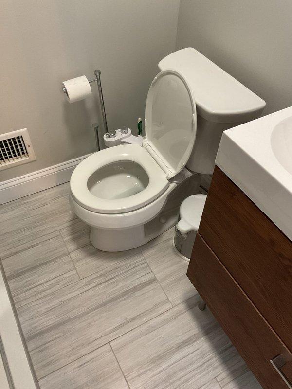 Completed plumbing repair service in residential property involving inspection and documentation of crawlspace plumbing infrastructure and bathroom fixtures. Assessed PVC drainage system beneath structure, examining multiple pipe connections, fittings, and joints for proper function. Documented condition of existing plumbing assembly including flexible conduit installation and various diameter pipe connections in crawlspace area. Verified bathroom fixtures including toilet installation and proper operation in corner-mounted configuration.