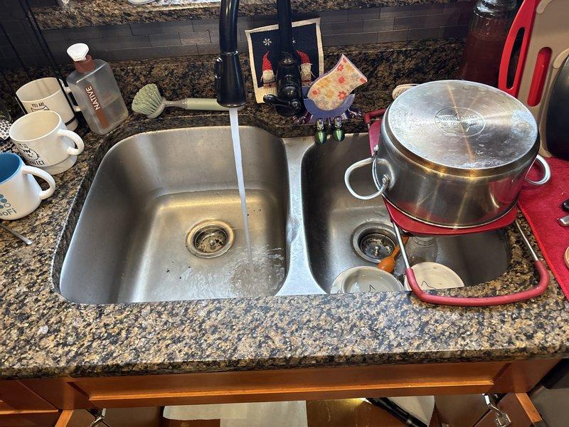 Responded to service call for kitchen sink leaking from underneath. Upon inspection, examined double-basin sink plumbing system and identified leak source at P-trap connection. Disassembled trap assembly, cleared minor debris accumulation, and inspected all PVC drain fittings for proper sealing. Reassembled drain system with secure connections, tested both basins for proper drainage and verified all joints were leak-free under running water.
