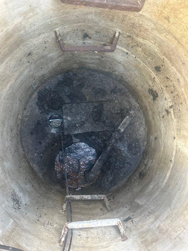 Conducted site assessment of existing 12-year-old ejector pump system located in below-grade concrete shaft. Documented current pump condition and surrounding infrastructure, noting significant accumulation of sediment and sludge at basin floor. Photographed shaft interior showing weathered concrete walls with embedded ladder rungs and visible moisture staining throughout structure. Prepared comprehensive estimate for ejector pump replacement based on observed system age, operational wear, and accumulated debris requiring removal during installation.
