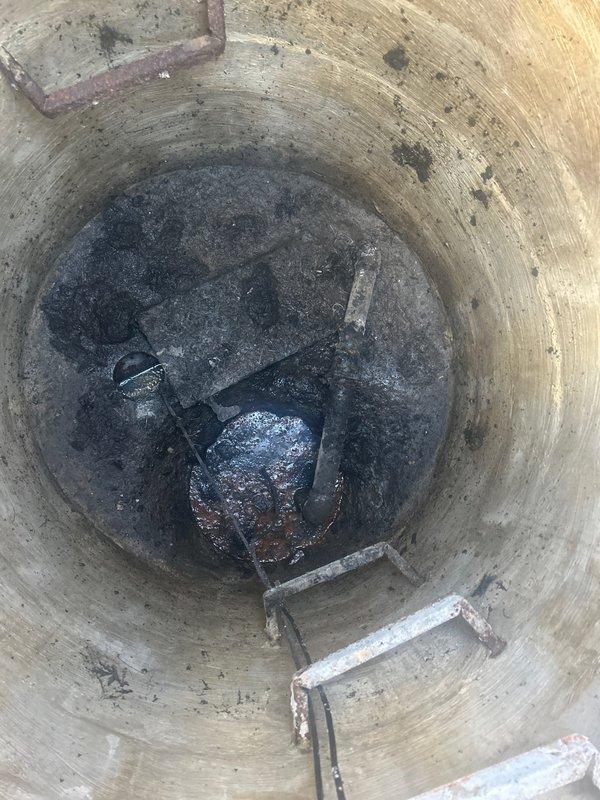 Conducted site assessment of existing 12-year-old ejector pump system located in below-grade concrete shaft. Documented current pump condition and surrounding infrastructure, noting significant accumulation of sediment and sludge at basin floor. Photographed shaft interior showing weathered concrete walls with embedded ladder rungs and visible moisture staining throughout structure. Prepared comprehensive estimate for ejector pump replacement based on observed system age, operational wear, and accumulated debris requiring removal during installation.