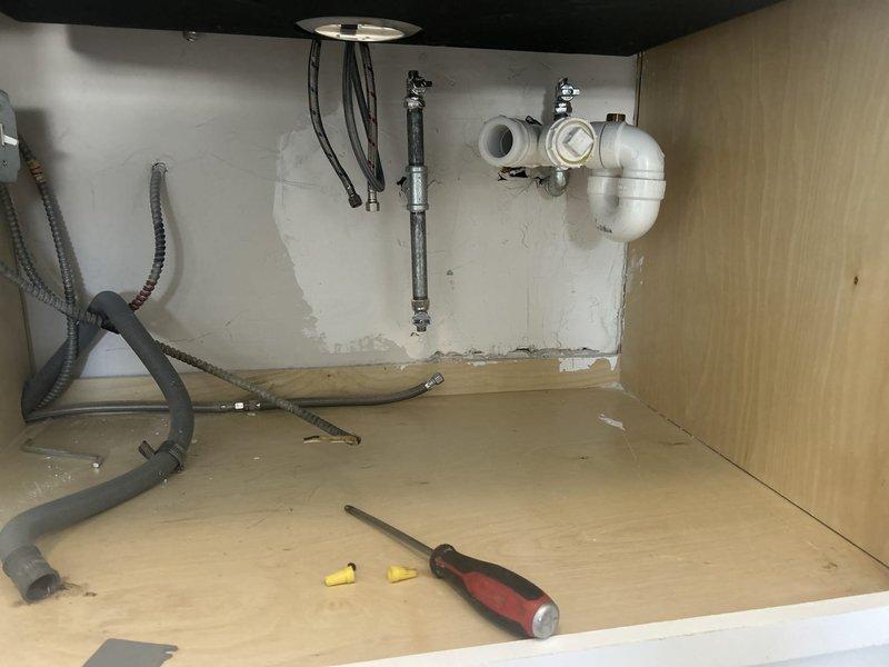 Completed installation of new under-sink plumbing components including white PVC P-trap assembly with chrome fittings and inline bottle trap with valve mechanism. Replaced flexible supply lines and reconnected all drain and water supply connections to ensure proper function and prevent leaks.