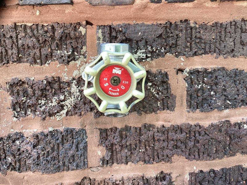 Responded to a call for an exterior water spigot with a leaking valve and a small pipe burst located outside the wall. Upon inspection, identified a deteriorated outdoor hose bib valve mounted on a weathered brick wall showing significant age and exposure damage. Assessed the valve assembly and surrounding plumbing infrastructure, documented the condition of the existing fixture and the compromised pipe section. Provided estimate for necessary repairs including valve replacement and pipe section repair to restore proper function and eliminate water loss.
