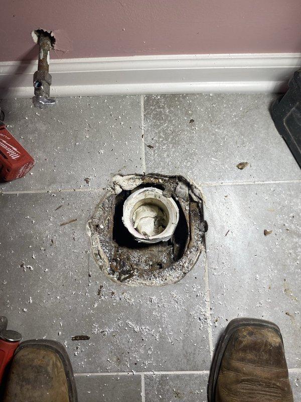Completed plumbing repair work involving toilet flange inspection and bathroom ventilation system assessment. Accessed wall cavity through existing opening to evaluate exhaust fan installation and verified proper mounting of bathroom ventilation unit. Inspected toilet flange assembly, noting accumulated debris and wear around the seal area, and assessed corroded water supply valve requiring attention for future maintenance considerations.