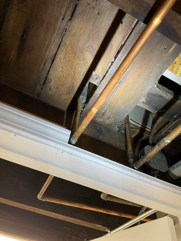 Responded to water leak complaint originating from second-floor bathtub usage and manifesting in basement ceiling area. Conducted thorough inspection of concealed plumbing systems within ceiling cavity, examining copper supply lines, drain assemblies, and surrounding structural components between floors. Located source of intermittent leaking in overhead plumbing infrastructure serving bathroom fixtures, with water bypassing first-floor areas and traveling directly to basement level through concealed pathways in floor joists and ceiling spaces.