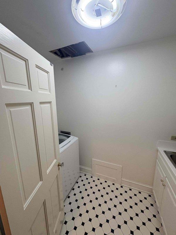 Conducted site assessment of laundry room plumbing system following initial service request. Documented existing conditions including exposed ceiling cavity above utility space, revealing copper supply piping and structural framing members. Photographed accessible plumbing infrastructure through ceiling access point and overall room configuration to support estimate preparation for proposed piping modifications or repairs.