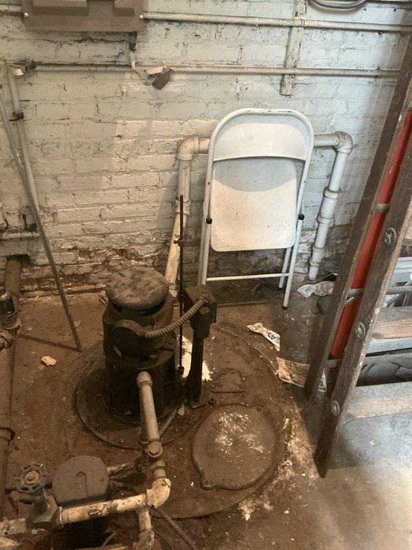 Responded to service call for malfunctioning sump pump producing excessive noise. Upon inspection, found heavily corroded and deteriorated sump pump system in basement utility area with significant age-related wear. Sump basin contained dark, sediment-filled water with visible debris accumulation. Concrete floor surrounding pump exhibited extensive water staining and damage patterns indicating chronic moisture issues and possible past flooding events. Primary pump unit showed advanced rust and corrosion on exterior housing with multiple pipe connections in compromised condition. Basement walls displayed peeling paint and moisture damage consistent with long-term water management problems. Documented existing conditions through photographic evidence for estimate preparation. Assessed complete sump pump replacement necessary due to equipment failure and deterioration beyond serviceable repair. Provided comprehensive evaluation of system requirements for proper water removal and basement 
