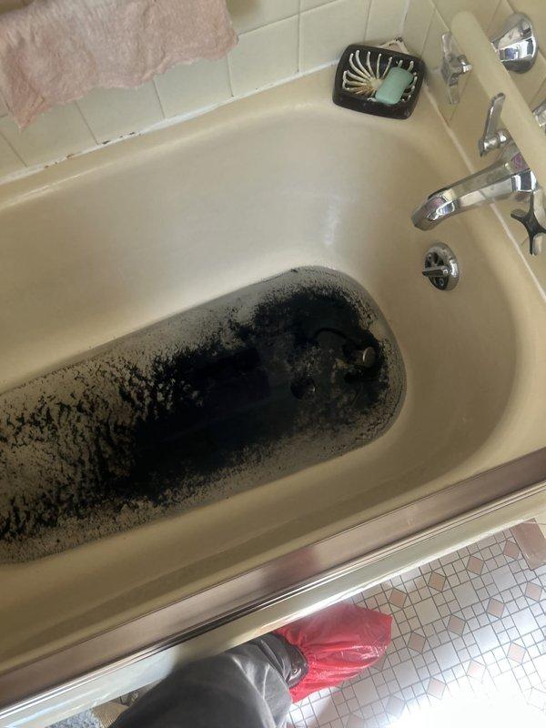 Responded to a clogged bathroom sink that was causing backup into the bathtub in an 80-year-old home. Upon arrival, found significant dark sediment and debris accumulated in the bathtub basin, indicating a substantial drainage blockage in the shared waste line. The homeowner had attempted unsuccessful DIY clearing methods over the previous two days before service call.

Assessed the plumbing configuration and determined the clog was located in the common drain line serving both fixtures. Utilized professional drain clearing equipment to access and clear the obstruction from the drainage system. Removed accumulated sediment, debris, and buildup that had caused the backup condition. 

Successfully restored proper drainage function to both the bathroom sink and bathtub. Verified water flow through both fixtures and confirmed no residual blockage remained in the waste lines. Left work area clean and advised homeowner on proper drain maintenance practices to prevent future occurrences in th