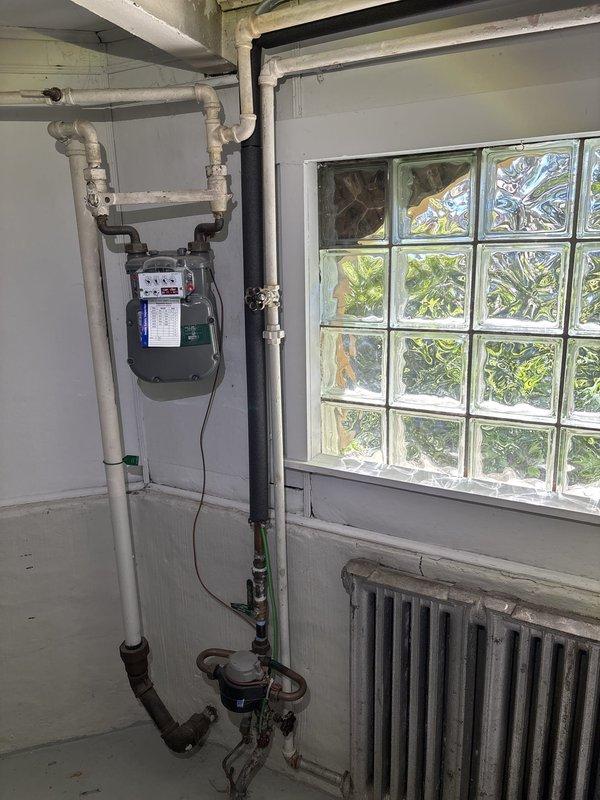 Responded to basement water leak complaint and identified source as heavily corroded valve assembly with active leakage at threaded bolt connection. Upon inspection, found extensive corrosion on valve body and brass handle with rust staining and mineral deposits throughout the plumbing system, indicating aged infrastructure. Documented existing conditions including deteriorated valve assembly, corroded piping connections, and compromised seals at threaded fittings for repair recommendation.