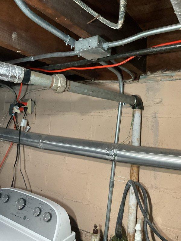 Responded to service call for kitchen sink backing up with slow drainage issues that had persisted over time. Accessed plumbing system through basement ceiling area where main drain lines run along floor joists. Inspected dual-basin sink plumbing configuration under vanity cabinet, including P-trap assembly and drain tailpieces. Located blockage in drainage system causing backup condition. Cleared obstruction from drain line to restore proper flow and drainage function. Verified both sink basins draining correctly upon completion. Documented existing plumbing infrastructure including PVC drain lines, supply lines, and condensate pump system present under sink cabinet.