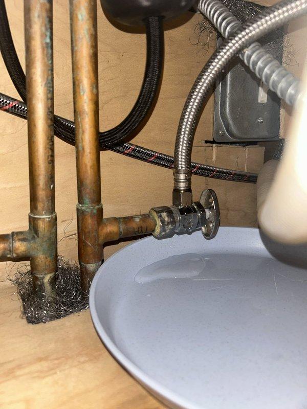 Responded to service call for two faucet issues: a kitchen sink leak occurring underneath when water was running, and a dripping faucet in an upstairs bathroom. Inspected kitchen sink plumbing and identified source of leak at supply line connections beneath the basin. Examined copper supply lines showing age-related oxidation and verified shutoff valve operation. Assessed upstairs bathroom faucet, a two-handle centerset chrome fixture with porcelain lever handles, to diagnose cause of drip. Documented existing plumbing conditions including aged copper piping with visible patina and corrosion. Provided assessment and repair recommendations for both fixtures to resolve leaking and dripping issues.