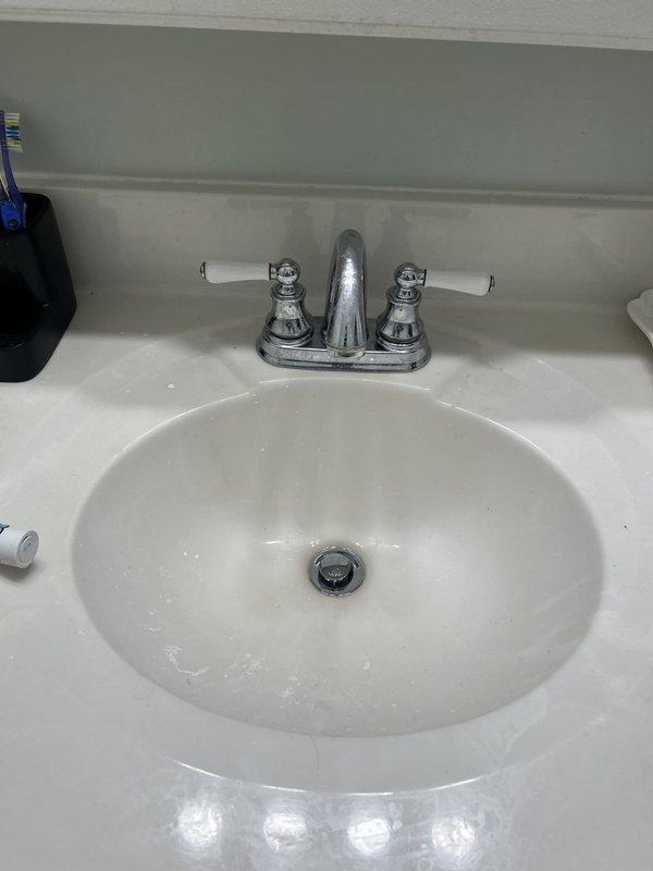 Responded to service call for two faucet issues: a kitchen sink leak occurring underneath when water was running, and a dripping faucet in an upstairs bathroom. Inspected kitchen sink plumbing and identified source of leak at supply line connections beneath the basin. Examined copper supply lines showing age-related oxidation and verified shutoff valve operation. Assessed upstairs bathroom faucet, a two-handle centerset chrome fixture with porcelain lever handles, to diagnose cause of drip. Documented existing plumbing conditions including aged copper piping with visible patina and corrosion. Provided assessment and repair recommendations for both fixtures to resolve leaking and dripping issues.