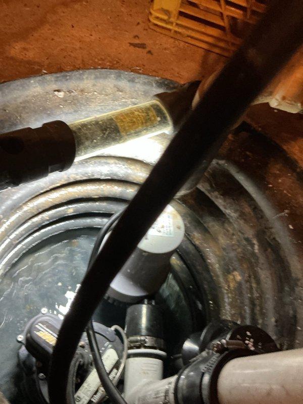 Responded to service call for non-functional sump pump battery backup system. Upon inspection, identified failed backup control unit and deteriorated electrical connections affecting the emergency power supply. Evaluated the primary sump pump assembly housed in cylindrical basin with associated discharge piping and verified main pump operational status. Assessed battery backup controller mounted on utility crate, noting compromised wiring connections and potential power supply failure to backup pump motor. Documented existing system configuration including PVC discharge lines, electrical routing, and backup component placement for estimate preparation. Provided customer with detailed assessment of battery backup system failure and recommended replacement of backup control unit and associated electrical components to restore emergency pumping capability during power outages.