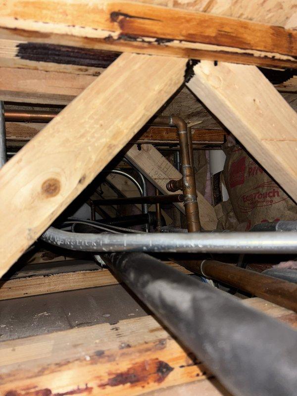 Completed tankless water heater installation in attic space, routing new copper supply lines and PVC venting through existing structural framework. Secured all piping connections with proper fittings and joints, ensuring compliance with code requirements for gas-fired tankless units in confined spaces with adequate combustion air and ventilation access.