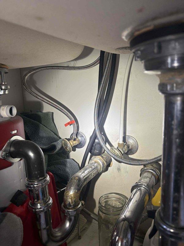 Responded to multiple plumbing leak concerns including kitchen and bathroom sink valve replacements, bathtub faucet repair, and toilet tank seal issues. Coordinated water shut-off with building management to safely replace leaking angle stop valves beneath kitchen sink and bathroom vanity. Inspected and documented existing plumbing configurations including P-trap assemblies, braided supply lines, garbage disposal connections, and wall-mounted shut-off valves. Assessed moisture accumulation around bathtub area to provide diagnostic evaluation and recommendations. Photographed under-sink plumbing conditions showing chrome fixtures, flexible supply lines, and drain assemblies for documentation purposes.