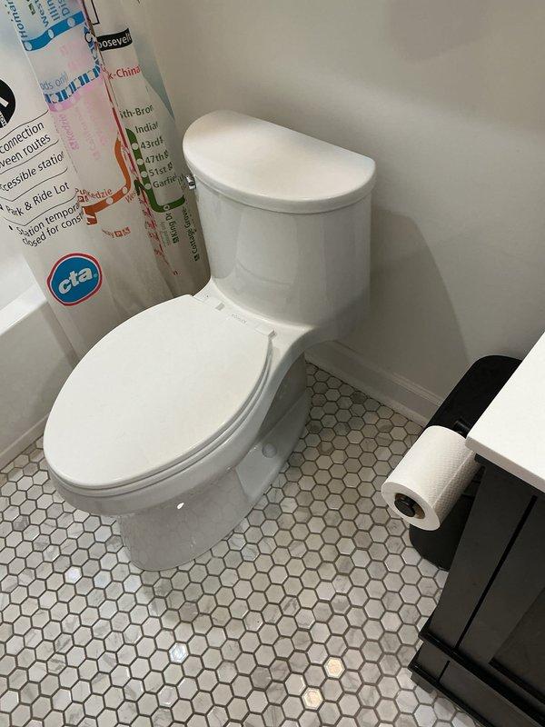 Responded to service call for sewer odor in bathroom area. Upon investigation, inspected bathroom fixtures and drainage system for potential sources of odor infiltration. Examined toilet installation, wax ring seal integrity, and floor flange condition using hexagonal tile flooring access points. Verified proper venting of drainage system and checked for dry trap conditions that could allow sewer gases to enter living space. Documented existing conditions through photographic evidence of bathroom fixtures and surrounding areas for service records.