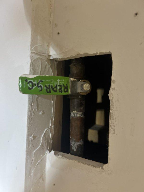 Accessed corroded horizontal supply line through wall opening to assess pipe condition and identify source of plumbing issue. Documented severely deteriorated metal piping with extensive corrosion, rust buildup, and mineral deposits requiring replacement. Cut access openings in ceiling and wall to expose affected plumbing infrastructure, revealing compromised copper supply lines and associated piping that necessitate full repair and restoration of water distribution system in affected area.