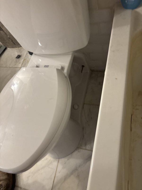 Diagnosed toilet supply line issue requiring replacement parts. Accessed plumbing connection through wall opening to evaluate water supply valve and surrounding area showing signs of water damage and mineral deposits. Parts have been ordered and follow-up appointment scheduled to complete installation of new supply line components and restore wall surface.