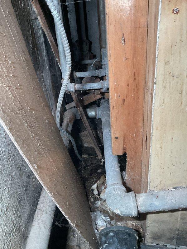 # Washing Machine Drain Backup - Basement

Responded to recurring drainage issue affecting basement washing machine drain line in 75-year-old residence. Customer reported backup had returned approximately two weeks prior, despite previous service 1-2 months ago. Upon arrival, accessed drain line through confined wall cavity space behind washing machine location.

Inspection revealed deteriorated drainage piping consistent with age of home's original plumbing infrastructure. Located blockage in main drain line serving washing machine discharge. Utilized mechanical auger to clear obstruction from drain system. Removed accumulated debris, soap residue, and sediment buildup that had reformed in aging cast iron or galvanized piping.

Given the recurrent nature of the blockage and advanced age of the plumbing system, advised customer that underlying pipe deterioration may be contributing to repeated backup issues. The original drainage piping shows signs of scale buildup and internal corrosi