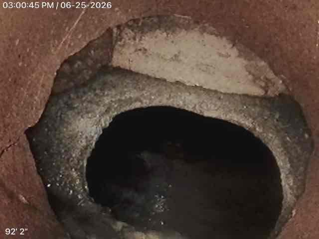 Completed comprehensive ejector pump inspection, accessing the below-grade pump basin through the existing concrete access pit. Visual assessment revealed standing water in the sump basin with visible debris accumulation and sediment present in the collection chamber. Documented current system conditions including deteriorated concrete collar edges, moisture levels, and water quality within the ejector pit, noting rust staining around the access opening perimeter. Photographic documentation captured for service records showing basin interior conditions and water accumulation levels.
