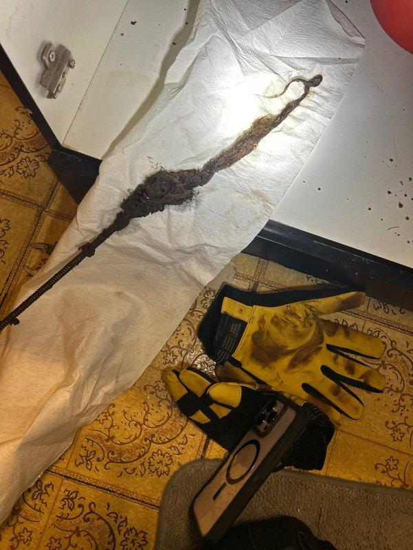 Responded to a clogged drain affecting both the bathroom sink and shower, where running the sink caused water backup in the shower. Removed a large accumulation of hair, soap residue, and organic debris from the shared drain line using mechanical extraction methods. Inspected the P-trap assembly and overhead drainage piping, noting existing water damage and rust staining on surrounding surfaces, and verified proper water flow through both fixtures upon completion.