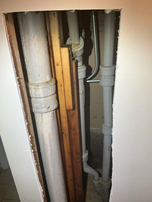 Responded to emergency service call for homeowner unable to use kitchen plumbing. Upon arrival, accessed main plumbing stack by opening interior wall to expose vertical drain and vent system. Located and repaired defective section of white PVC waste line running between wall studs. Work included cutting away drywall to access compromised piping, replacing damaged fittings and joints on main drain stack, and addressing issues with secondary gray PVC drain lines and associated couplings. All plumbing connections tested and verified operational to restore full kitchen functionality.
