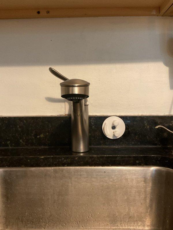 Completed kitchen faucet installation including connection of braided supply lines to existing water supply valves and mounting of brushed stainless steel soap dispenser on countertop. All connections were tested and verified leak-free with proper water flow and drainage confirmed through the undermount stainless steel sink.