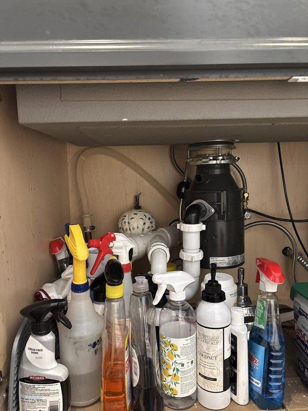 Responded to priority request for plumbing disconnection in preparation for countertop installation. Assessed kitchen sink area with existing white PVC plumbing, black garbage disposal unit, and associated supply lines beneath cabinet. Also evaluated bathroom shower assembly featuring chrome fixtures, control valves with cross-handle design, and flexible braided metal supply hose connected to diverter spout. Documented existing plumbing configurations and fixture connections to facilitate upcoming countertop replacement work.