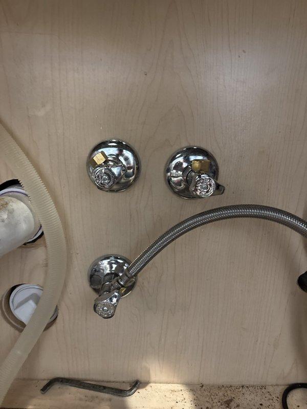 Responded to priority request for plumbing disconnection in preparation for countertop installation. Assessed kitchen sink area with existing white PVC plumbing, black garbage disposal unit, and associated supply lines beneath cabinet. Also evaluated bathroom shower assembly featuring chrome fixtures, control valves with cross-handle design, and flexible braided metal supply hose connected to diverter spout. Documented existing plumbing configurations and fixture connections to facilitate upcoming countertop replacement work.