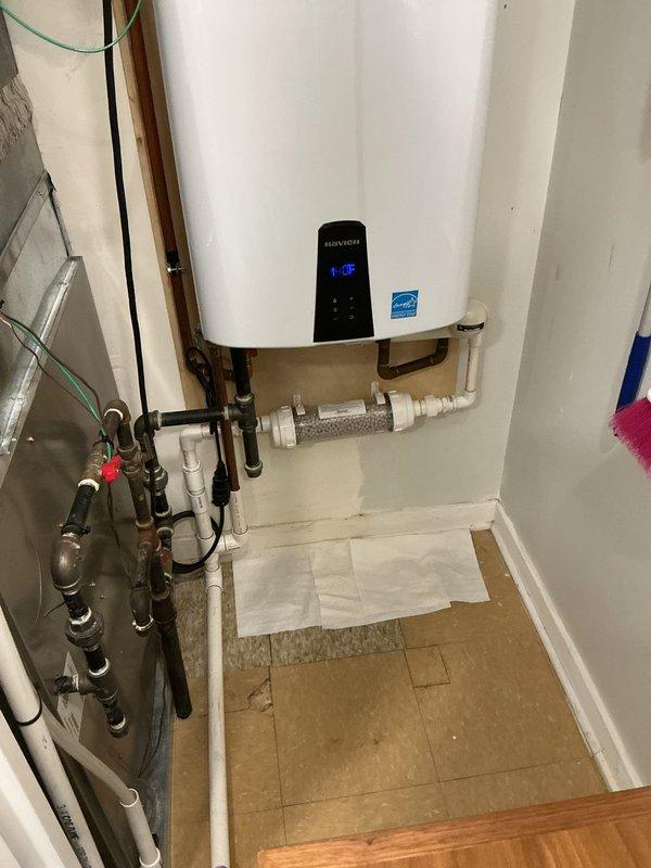Completed installation of Navien tankless water heater system with Energy Star certification. Replaced failed component and established all necessary plumbing connections using white PEX piping with brass fittings, flexible braided supply lines, and copper piping integration. Installed inline water filtration system with clear housing and filtering media to protect unit from sediment and mineral buildup. Configured digital control panel and verified proper temperature settings and system operation. Mounted unit securely to wall in utility closet, ensured all electrical connections were properly terminated, and tested hot water delivery throughout the residence. All connections sealed and pressure-tested to confirm leak-free operation.