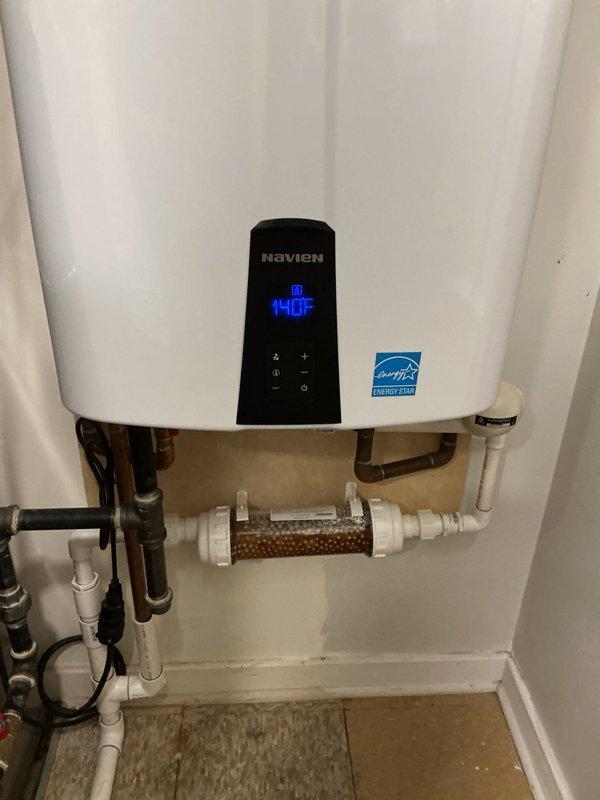 Completed installation of Navien tankless water heater system with Energy Star certification. Replaced failed component and established all necessary plumbing connections using white PEX piping with brass fittings, flexible braided supply lines, and copper piping integration. Installed inline water filtration system with clear housing and filtering media to protect unit from sediment and mineral buildup. Configured digital control panel and verified proper temperature settings and system operation. Mounted unit securely to wall in utility closet, ensured all electrical connections were properly terminated, and tested hot water delivery throughout the residence. All connections sealed and pressure-tested to confirm leak-free operation.