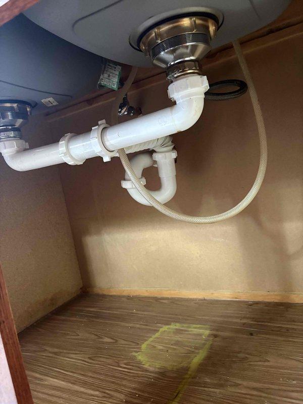 Conducted on-site evaluation of existing kitchen sink plumbing to assess installation requirements for a reverse osmosis water treatment system. Inspected under-sink cabinet space, photographed current drain assembly consisting of white PVC P-trap configuration with chrome strainer basket, and documented available space for RO system components. Evaluated water supply lines, shut-off valves, and drain connection points to determine optimal placement and necessary modifications for reverse osmosis unit installation, then provided comprehensive estimate for system installation.