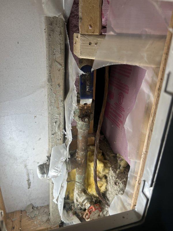 Responded to a plumbing repair call where corroded copper piping was discovered within an interior wall cavity showing significant oxidation, mineral deposits, and signs of water damage. Removed damaged section of drywall to access the compromised pipe, replaced the deteriorated plumbing line, and located the main water shutoff valve in the yard to isolate the system during repairs.