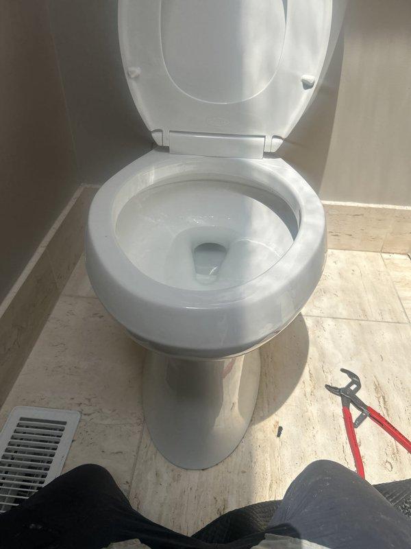 Responded to service call for toilet leaking from the bottom. Upon inspection, identified water leakage at the base of the toilet with visible water staining and discoloration on the floor tiles surrounding the toilet flange area. Diagnosed issue as likely wax ring failure or compromised toilet base seal, requiring toilet removal and reinstallation with new wax ring and flange hardware to resolve the leak and prevent further water damage to the flooring.