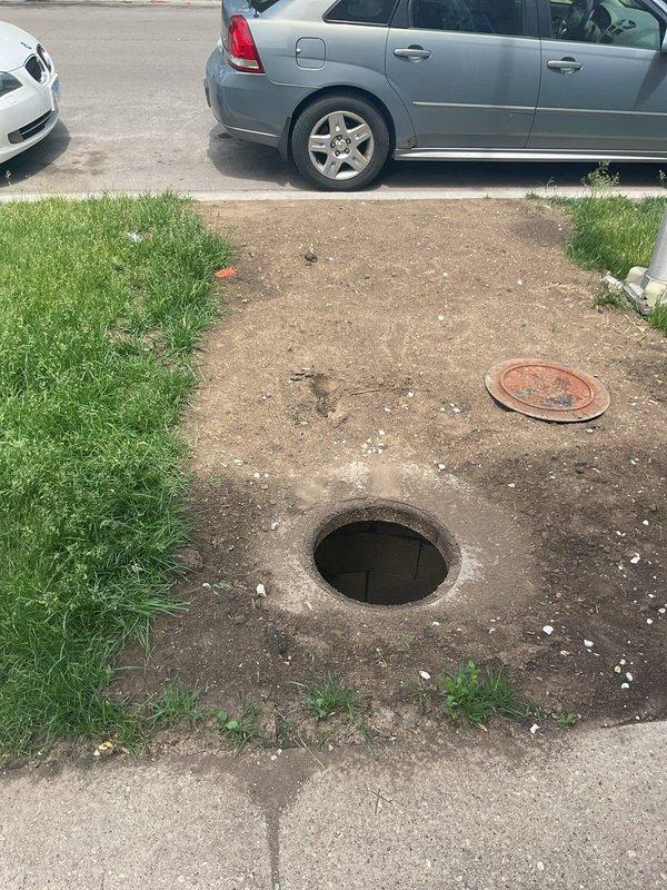 Accessed underground utility vault to inspect and assess corroded water valve assembly. Removed vault cover to expose horizontal pipe system with center valve showing significant rust deterioration and standing water accumulation in chamber requiring drainage and valve replacement evaluation.