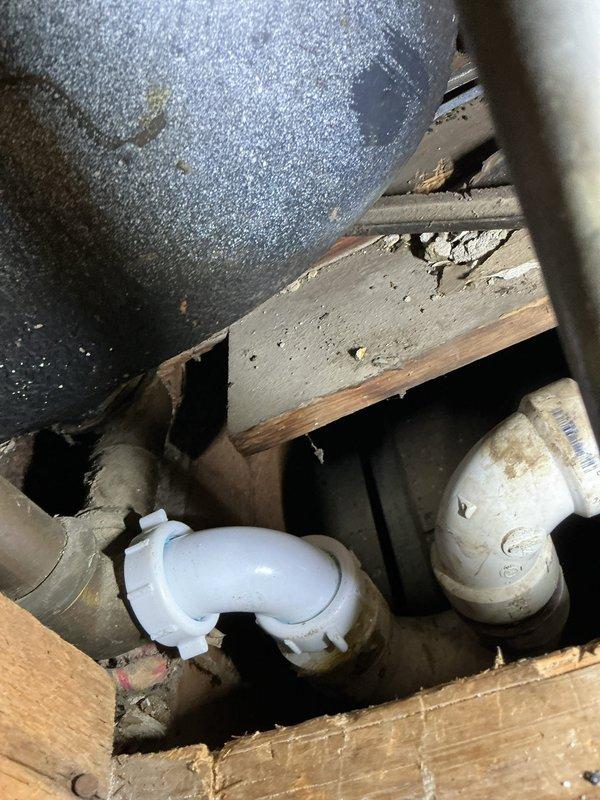 Responded to service call for slow-draining bathtub and shower handle inspection. Upon arrival, assessed bathroom fixtures including tub drain assembly and shower control valve. Inspected bathtub drain stopper mechanism and identified visible mineral deposits and rust staining near drain opening indicating potential buildup within drain line. Accessed crawlspace beneath bathroom to examine drainage plumbing infrastructure, noting connection points between white PVC piping and older galvanized drain lines. Evaluated shower valve assembly with temperature control handle and diverter spout for proper operation and potential replacement needs.