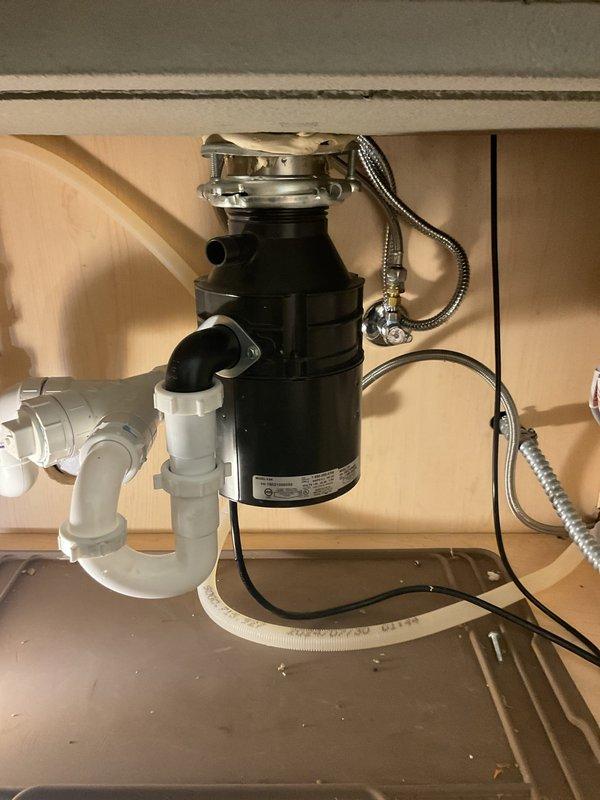 Initiated installation of professional-style chrome kitchen faucet with pull-down sprayer on marble countertop island and installed new garbage disposal unit with connected PVC P-trap drainage system. Work remains incomplete per customer request for different technician to return and finalize installation and collect payment.