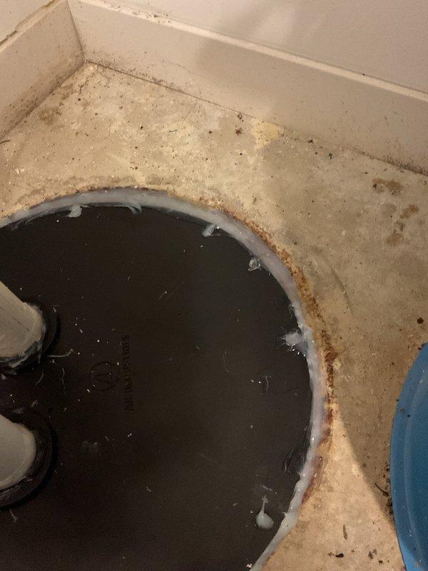 Responded to callback for improperly sealed ejector basin. Upon inspection, found standing water and debris accumulation in basin with rust-colored staining along seams and corners, indicating seal failure at basin perimeter. Observed two PVC discharge pipes extending through rubber sealing boot with visible moisture and residue around edges, confirming inadequate seal at pipe penetrations. Re-sealed ejector basin assembly and pipe penetrations to manufacturer specifications to prevent future water infiltration and ensure proper wastewater containment.