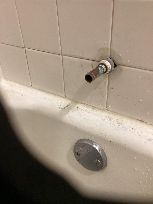 Responded to emergency building shutdown to address bathtub and shower fixture failure. Removed deteriorated chrome tub spout and shower valve assembly from white subway-tiled wall, exposing copper supply lines for replacement. Installed new chrome bathtub faucet and shower control system with updated valve trim plate and clear acrylic control handle, ensuring proper connections to existing plumbing infrastructure and restoring full water service to the fixture.