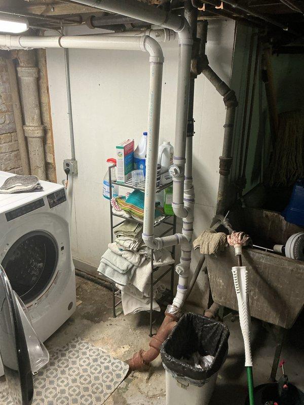 Conducted comprehensive assessment of main sewer line from house to municipal connection, water supply line, and catch basin drainage system in 130-year-old residential property. Inspected basement utility area revealing aged cast iron waste piping with visible corrosion, existing PVC drainage modifications, and deteriorated concrete foundation walls showing efflorescence and moisture intrusion. Documented existing plumbing infrastructure including corroded vertical stack, laundry drainage system, and copper water supply lines to provide detailed replacement estimates for main sewer lateral, water service line upgrades, and catch basin repairs necessary to address aging infrastructure concerns.